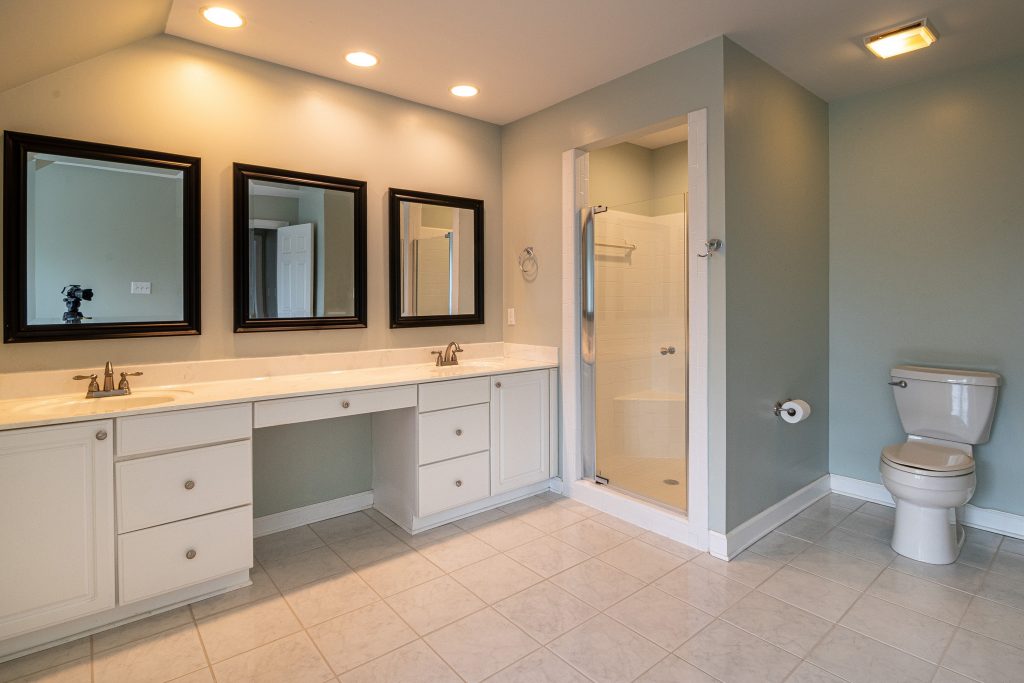 stock image of bathroom with built in shower and counters with three large mirrors
