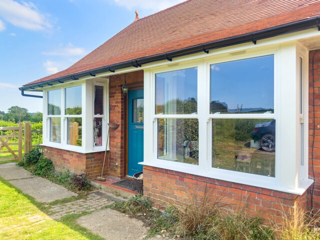 Beautiful period brick cottage featuring authentic-looking white uPVC sash windows with traditional proportions, demonstrating how modern uPVC windows perfectly complement heritage architecture while providing energy efficiency and low maintenance benefits bay windows