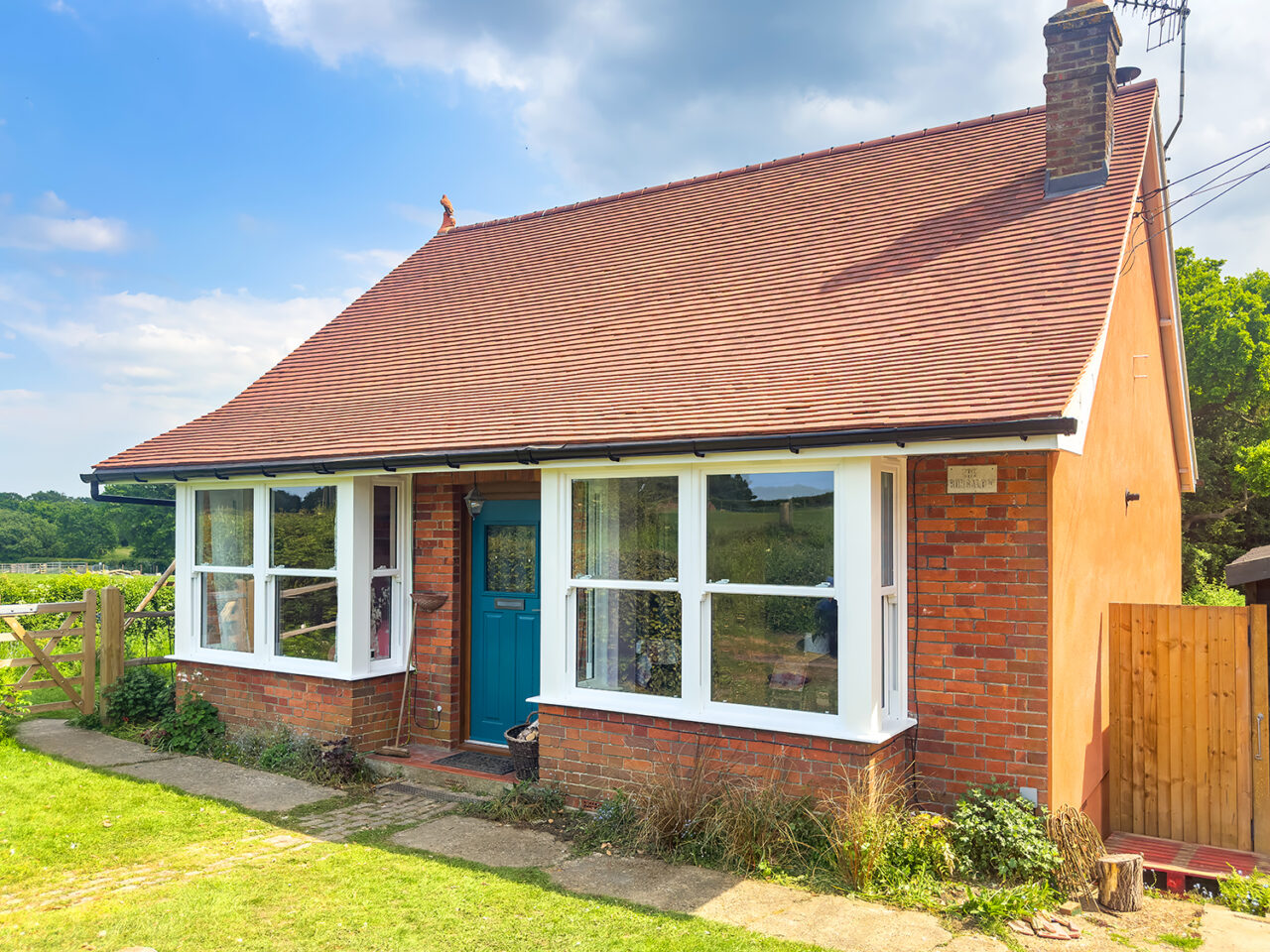 Beautiful period brick cottage featuring authentic-looking white uPVC sash windows with traditional proportions, demonstrating how modern uPVC windows perfectly complement heritage architecture while providing energy efficiency and low maintenance benefits